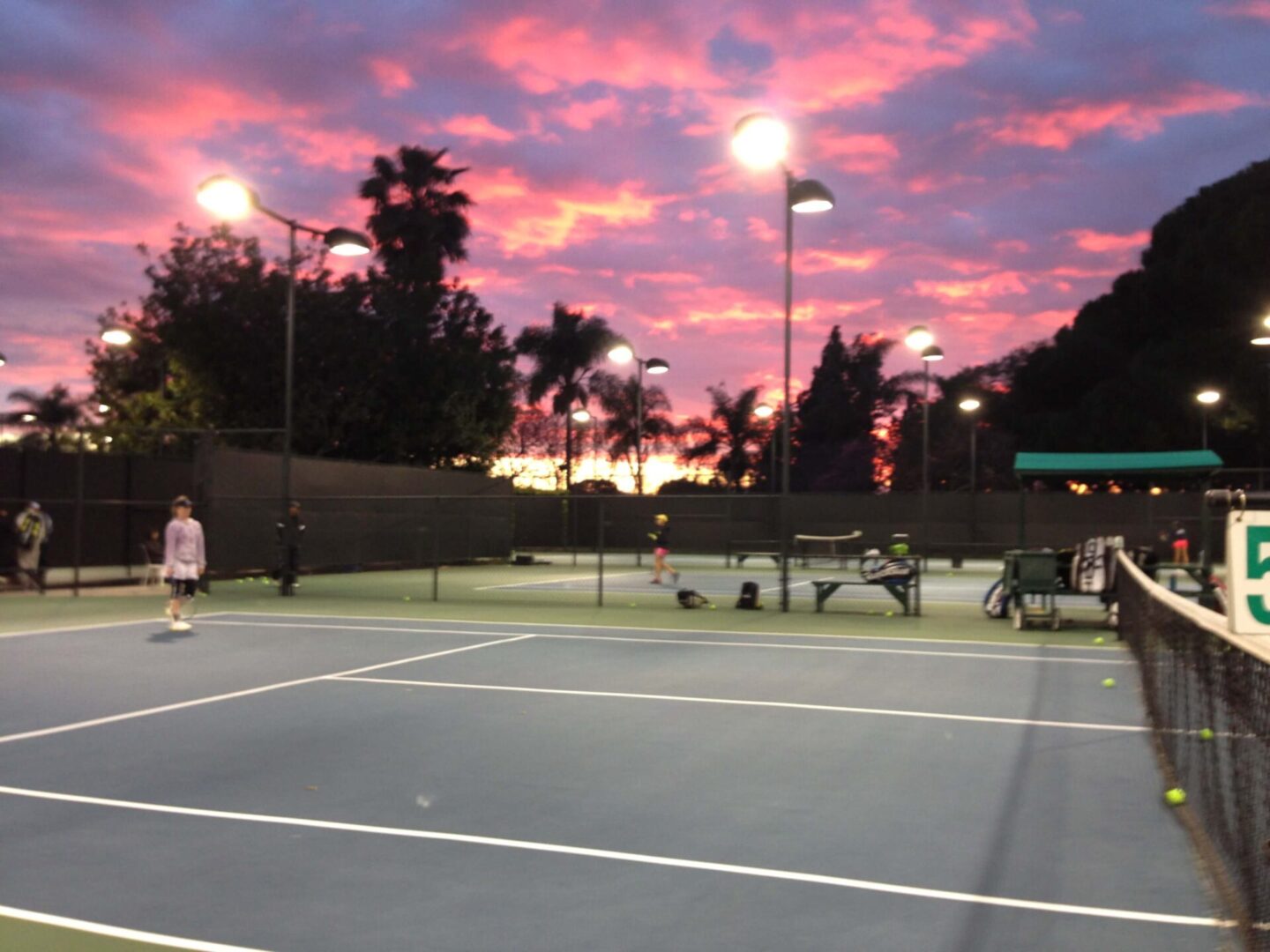 A Tennis Court With a Pink and Purple Sky