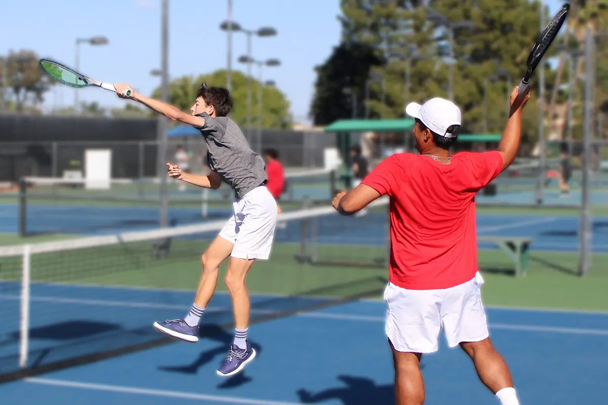 Two players volleying on outdoor tennis court