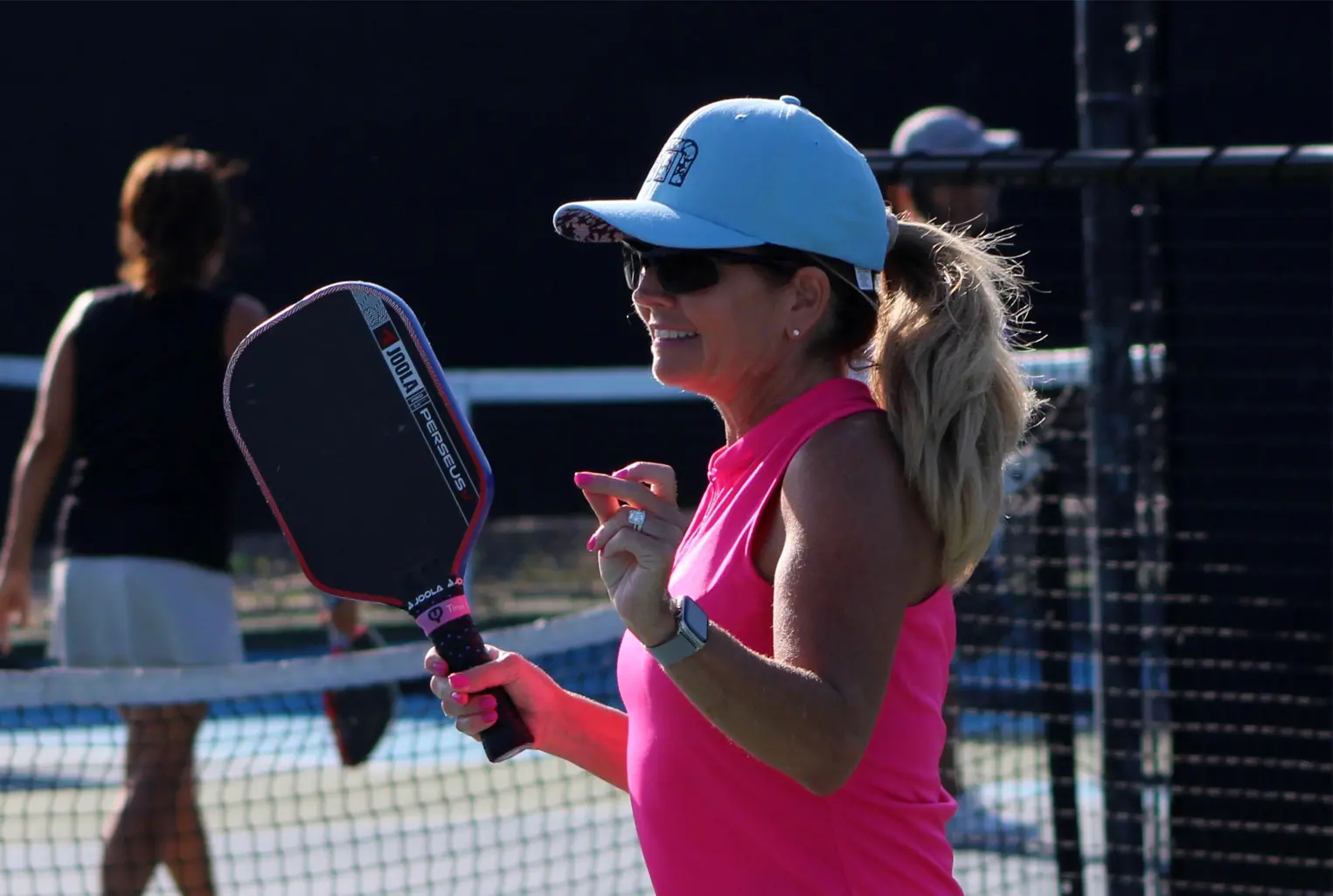 Woman playing pickleball in pink top