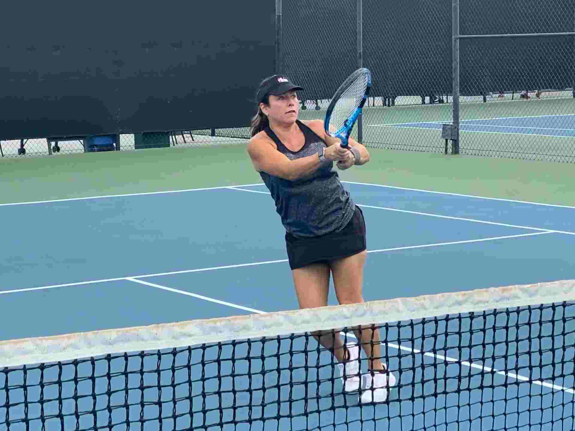 Woman playing tennis on outdoor court.
